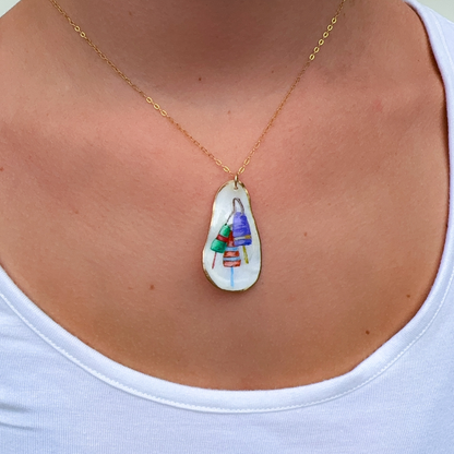 Close-up of hand-painted buoy design on a coastal oyster shell necklace pendant