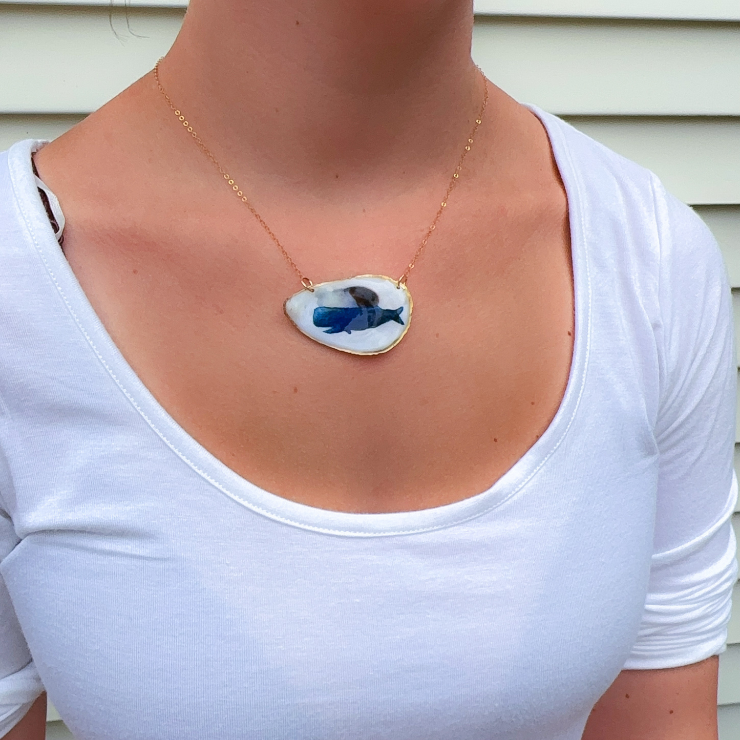 Close-up of hand-painted whale design on a coastal oyster shell necklace pendant
