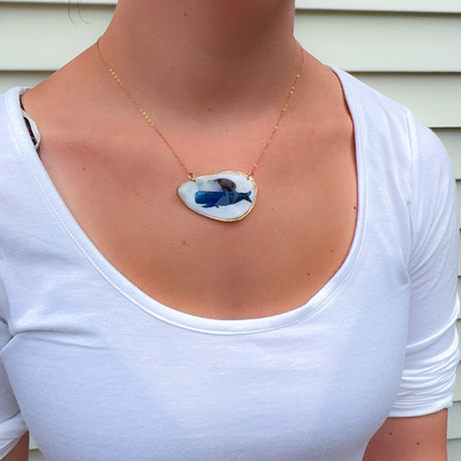 Close-up of hand-painted whale design on a coastal oyster shell necklace pendant