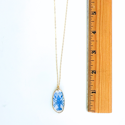 One-of-a-kind blue lobster oyster shell necklace styled on a neutral background