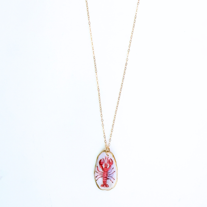 One-of-a-kind red lobster oyster shell necklace styled on a neutral background